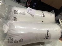 Two IKEA standard pillows, white, packaged in clear plastic with printed labels showing dimensions and fabric content.