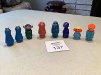Nine Fisher Price Sesame Street character toys in a row on a white table, showing all figures from left to right.
