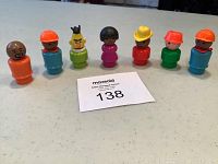 Seven vintage Fisher Price Little People figures and one Bert Sesame Street figure on a table with MaxSold auction label.