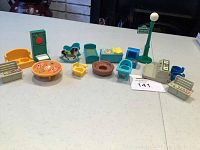 Full grouping of multiple Fisher-Price vintage dollhouse furniture and Sesame Street toys arranged on a white table.