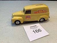 Front side view of yellow Home Hardware van bank showing details of decals, headlights, and coin slot on roof.