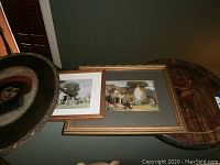 Overall view of three art pieces: round painted plaque, two framed paintings, and one oval plaque