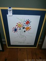 Framed Picasso print showing colorful floral bouquet with hands drawing, full view.