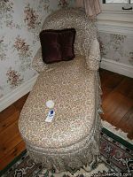 Settee chaise lounge showing floral upholstery, skirted base, and shape.