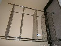 Full view of metal shelving unit showing five wire shelves and four vertical support poles with caster wheels.