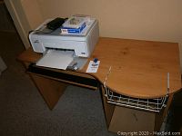 Wide view showing HP Photosmart printer and particle board desk with wire basket and keyboard tray