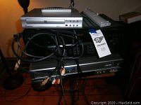 Stack of devices including CyberHome DVD player (silver), Sony A/V Control Center, Samsung DVD/VCR combo with attached AV cables