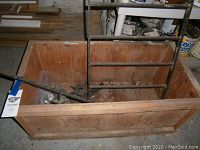 Wooden box containing various vintage metal items inside, showing box construction and contents from above
