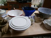 Overview of collection on table showing bowls, pitchers, and containers in various sizes and materials arranged together
