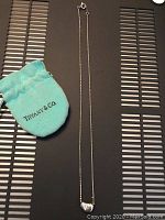 Tiffany & Co. heart pendant necklace laid out with a Tiffany blue pouch on a flat surface