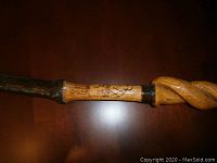 Close-up of the walking stick handle and upper shaft showing the carved spiral design and transition band.