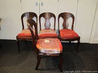 Four walnut veneered chairs with rounded backs, cabriole legs, and red fabric seats showing wear, arranged in a room.