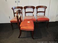 Front view of four walnut veneered dining chairs with worn red upholstered seats for sale.