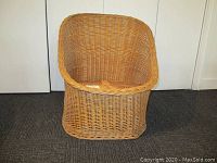 Front-facing view of a vintage low wicker chair, showcasing the rounded back and woven wicker design.