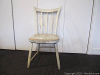Front view of the antique arrow back chair showing the overall structure, sloped back, and worn paint.