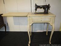 Full view of the off-white sewing table with fold-out extension open and White brand sewing machine mounted on top.