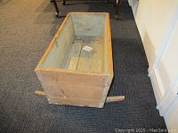 Full view of the rustic old wooden baby cradle showing wear and one missing rocker.