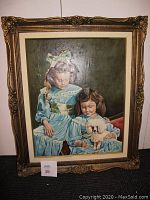 Frontal image showing the full framed oil painting of two girls holding a dog, with an ornate gold painted wooden frame.