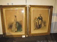 Two large framed portraits of Napoleon III and Eugenie of France standing side by side against a white wall.
