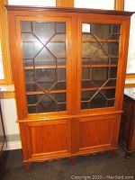 Full view of the vintage wooden bookcase showing upper glass paneled doors and lower solid doors with tapered legs.
