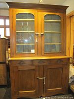 Front view of cupboard showing glass-fronted upper cabinet and lower drawers and doors