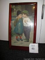 Full view of framed print showing two boys talking in old-fashioned clothing, wood frame with some wear