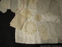 Photo of assorted vintage linens and doilies spread over a surface showing various crocheted and lace designs, silk handkerchiefs, and linen fabrics.