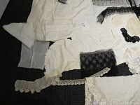 All items spread out including slips, lace trims, black and white lace pieces, doilies, embroidered textiles.