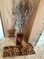 Full view of the vase with decorative stems arranged inside and additional decorative stems laid out in front
