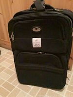 Closed black expandable Leisure suitcase showing front storage compartments and wheels