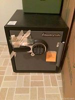 Front view of Sentry safe showing digital keypad and handle, taped with protective tape, door closed and locked.