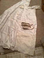 Full view of wedding dress laid out with train slip, veil, and shoes on carpeted floor