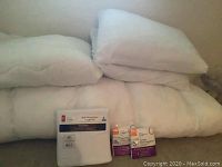 Full view of mattress topper, cover, two pillows, and packaged sheets and pillow protectors.