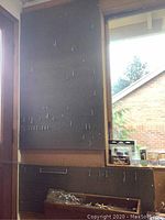 Wall-mounted pegboards with assorted small hooks and some hardware pieces attached. Mostly empty, providing a backdrop.
