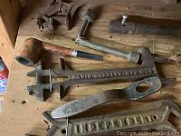 Old and rusty pipe wrench labeled 'David Bradley', large hand tools including adjustable wrench and clamp, all showing heavy use and rust.