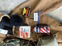 Photo of Carhartt jacket with hood, band-aid box, razor blades, brush, and car wax bottle on floor