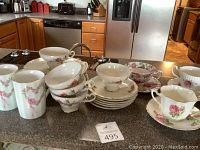 Photo of Bone China cups, saucers, and dessert plates on kitchen counter, showing floral patterns.