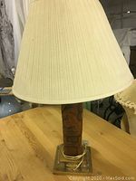 Photo of entire lamp showing carved wooden tiki base and pleated fabric shade