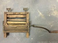 Top-down photo of antique wooden wringer washing machine showing rollers and metal crank handle