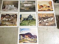 Seven art prints laid out on the floor displaying various landscapes and buildings.