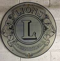 Full front view of the round metal Lions Club International sign showing the entire logo and text.