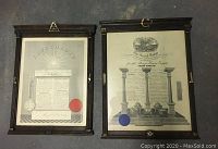 Two framed Masons certificates laid on floor, showing full certificates and frames
