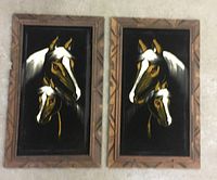 Both black velvet horse paintings with carved wooden frames side by side on a floor.