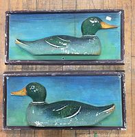 Front view of two rectangular wooden plaques each with a dimensional plaster mallard duck mounted, painted blue and green background.