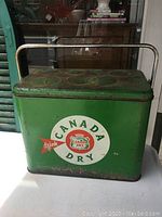 Front view of the vintage Canada Dry cooler showing the logo and metal handle.