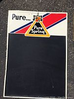 Full view of the metal chalkboard sign featuring Pure Spring branding and black chalkboard area.