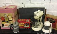 Photo showing the seven vintage kitchen appliances including mixers, coffee makers, a food chopper and their original boxes.