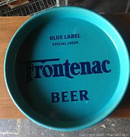 Full view of the round turquoise metal tray with Frontenac Beer Blue Label Special Lager branding centered.
