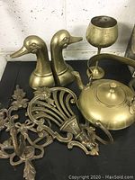 Front view of all six brass and metal decorative pieces together on black surface.