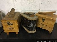 Three vintage shoe shine kits side by side, showing wooden and metal cases with handles and latches.